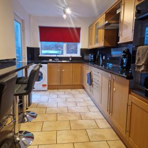cocina con armarios de madera, lavadora y secadora en Belfast Central house, en Belfast