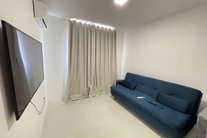 a living room with a blue couch and a flat screen tv at Imóvel Novo, 4 Quartos, Ar Condicionado em todos ambientes - Cond. Fechado - Guarajuba-BA in Camaçari
