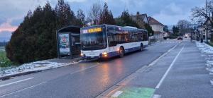 a bus parked at a bus stop on a street at Agréable chambre in Prévessin-Moëns
