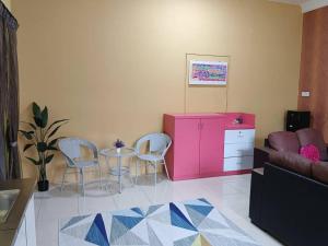 a living room with a table and chairs and a pink cabinet at Homestay Moslim Kampung Bentong in Kluang
