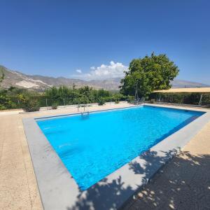 ein großer blauer Pool mit Bergen im Hintergrund in der Unterkunft Casa rural en Padul entre Sierra Nevada y la Costa in Granada
