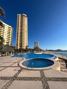 een zwembad naast een strand met hoge gebouwen bij Gavias Grand Cerritos in Mazatlán
