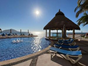 een zwembad met stoelen en een parasol en de oceaan bij Gavias Grand Cerritos in Mazatlán