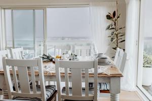 a dining room with a table and white chairs at Sailor's Catch in Hokitika
