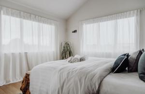a bedroom with a large white bed with white curtains at Sailor's Catch in Hokitika