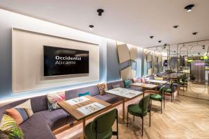 a restaurant with tables and chairs and a tv on the wall at Occidental Alicante in Alicante