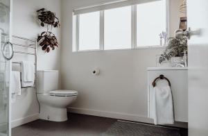 a white bathroom with a toilet and a window at Sailor's Catch in Hokitika