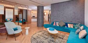 a living room with a blue couch and a chair at Occidental Alicante in Alicante