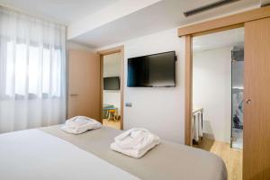 a bedroom with a bed with white sheets and a flat screen tv at Occidental Alicante in Alicante