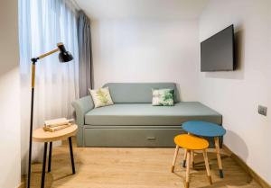 a living room with a couch and a table and stool at Occidental Alicante in Alicante