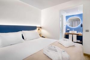 a bedroom with a white bed and a mirror at Occidental Alicante in Alicante