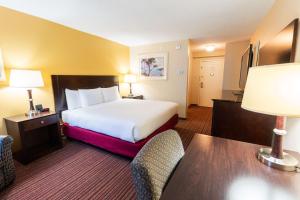 Una habitación de hotel con una cama, un escritorio y sillas. en Fireside Inn & Suites Portland, en Portland