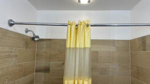 a shower with a yellow shower curtain in a bathroom at Relax Inn Altoona in Altoona +29 photos