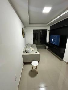 a small living room with a couch and a stool at Apto 2 quartos perto da praia in Rio de Janeiro