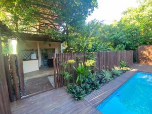 a backyard with a wooden fence and a swimming pool at Flat com piscina e perto do mar Taipus in Marau
