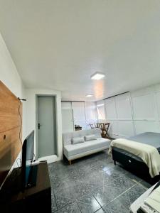 a living room with a couch and a bed and a tv at Apartamento Asa Norte com Varanda in Brasilia