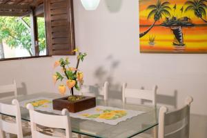 ein Esszimmer mit einem Glastisch und weißen Stühlen in der Unterkunft CASAS DE VERANEIO -Temporada - Barra de São Miguel in Barra de São Miguel