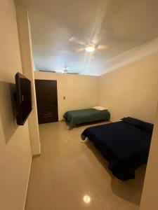 a small room with two beds and a tv at Suites Mar de Cortes in Mazatlán +7 photos