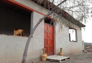a building with a red door and two vases at Mar de Estrellas in Cachí