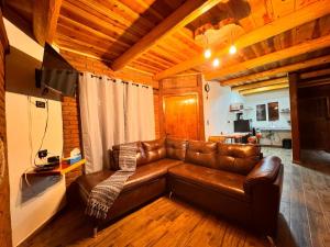 a brown leather couch in a living room with a television at Cabañas Villa Escondida in Urique