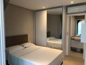 a bedroom with a white bed and a mirror at Residencial Estanconfor com Vista Mar AC e garagem in Santos
