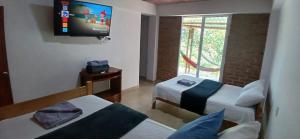 a room with two beds and a flat screen tv at Entre Aves hospedaje in Luna Park