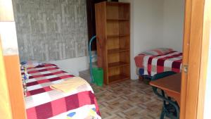 a room with two beds and a table and a desk at Hospedaje Arvakeni in San Cristóbal