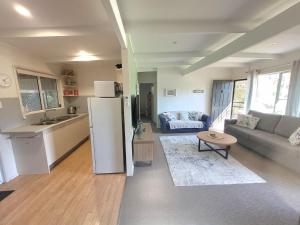 a kitchen and a living room with a refrigerator at Waterfront Retreat by Book Jervis Bay Getaway Kayaks, Bikes, Fast Wi-Fi and more in Sanctuary Point