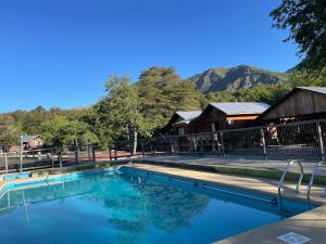 a swimming pool with a barn and mountains in the background at Cabañas Mawidantu Lemu in Las Trancas