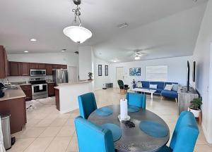 a kitchen and living room with a table and blue chairs at Experience Fun Starts Here w Pool & Wifi in Port Charlotte