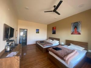 two beds in a room with a ceiling fan at Kumaon Gud Chaha Cafe & Homestay in Chaukori