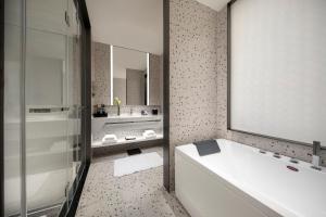 ein Badezimmer mit Badewanne, Waschbecken und Spiegel in der Unterkunft voco Shanghai Zhangjiang by IHG in Shanghai + 41 Fotos