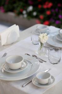 una mesa blanca con platos y tazas y una flor en un jarrón en Hotel Gala, en Riccione