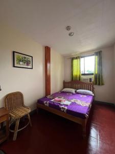 a bedroom with a bed and a chair and a window at Princesa el gallo inn in Puerto Princesa City