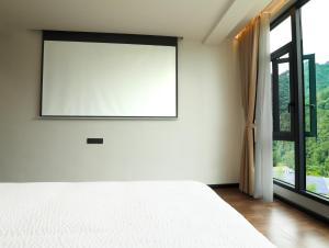 a bedroom with a white bed and a large window at 张家界喜屋民宿 in Zhangjiajie