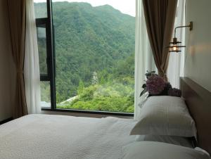 a bedroom with a bed and a large window at 张家界喜屋民宿 in Zhangjiajie