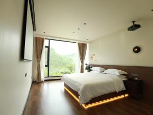 a bedroom with a large bed and a large window at 张家界喜屋民宿 in Zhangjiajie