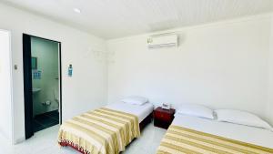 two beds in a white room with a bathroom at Keylee's Lodging in San Andrés