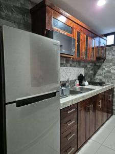 a kitchen with a white refrigerator and wooden cabinets at Casa Girasoles Valladolid Yucatán in Santa Bárbara