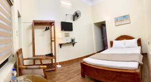 a bedroom with a bed and a chair and a tv at Khách Sạn Hùng Vân in Ha Giang