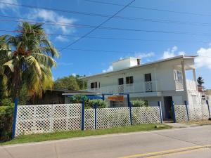 a white house with a fence and a palm tree at Keylee's Lodging in San Andrés