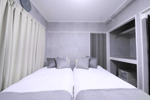 two beds in a small bedroom with white walls at 1 line to Asakusa! Modern Room, 5 mins walk from Togoshi-ginza Sta in Tokyo
