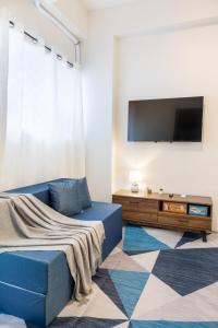 MandurriaoにあるAesthetic 2Bedroom loftの青いソファと薄型テレビのあるリビングルーム