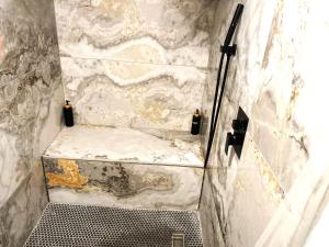 a walk in shower with a marble wall at Cozy Studio Loft Near Downtown in Columbus +2 photos