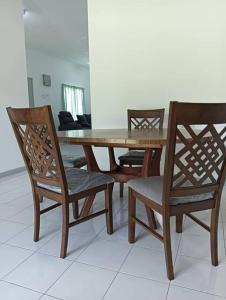 a wooden table with four chairs and a wooden table and chairs at Orchard Lake House - Entire bungalow, 4 rooms, 9 beds, 13 persons in Behrang Hulu