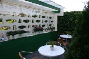 a patio with two tables and a green wall with plants at Hotel Haus Wittwer in Emden