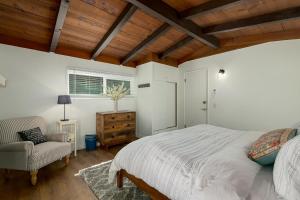 a bedroom with a bed and a chair and a window at The Brook Ave Bungalow in Kings Beach