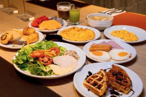 a table with plates of breakfast food on it at PARKROYAL Suites Bangkok in Bangkok