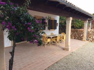a table and chairs on a patio with purple flowers at Sa Bassa Crua Agroturismo in Sa Torre