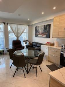 una cucina e un soggiorno con tavolo e sedie in vetro di New Luxury Walkout Suite Near University a Calgary